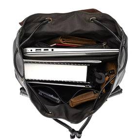 Experience the versatility of the Vintage Leather Backpack, seen from above in black. It perfectly accommodates a laptop, spiral notebook, two brown pouches, a camera, and other small essentials—your ideal travel companion.