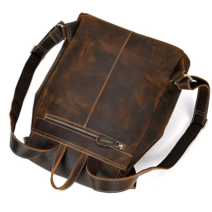 The Vintage Leather Backpack, made from authentic cowhide leather, features adjustable shoulder straps, a top handle, and a horizontal zippered pocket on the back. Its rugged distressed finish with visible stitching makes it ideal for stylishly transporting your travel essentials.