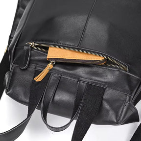 A close-up of the Vintage Leather Backpack showcases a partially open zippered pocket. The zipper is gold with a tan leather tab visible, complemented by black canvas straps, ideal for travel essentials.
