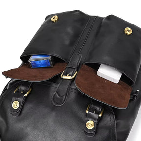 Close-up of the Vintage Leather Backpack made from genuine cowhide leather, showcasing two front pockets. The left pocket contains a blue cigarette pack, while the right pocket holds a white rectangular object. Both pockets feature brown suede lining and secure with brass button closures—perfect for travel essentials.