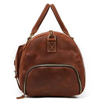 The Weekender 23 Leather Travel Bag, made from genuine cowhide leather in a sophisticated brown hue, showcases a structured, rounded design. It features a front zippered pocket, dual top handles with visible stitching, and elegant brass hardware accents. The bag is equipped with a zipper closure and a small loop detail on the front, making it ideal for weekend travels.