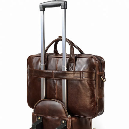 The Leather 16" Briefcase, crafted from genuine cow leather, is securely attached to the extended handle of a rolling suitcase. The suitcase handle fits through an adjustable strap on the back of the briefcase, which features a pair of sturdy handles and a sleek design.