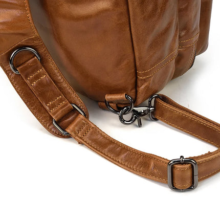 Close-up view of the Leather Travel Backpack Shoulder Bag detail, showcasing adjustable straps with black metal buckles and a side hook attachment. The genuine cowhide leather appears smooth and well-crafted, highlighting the quality and durability of this luxury accessory.