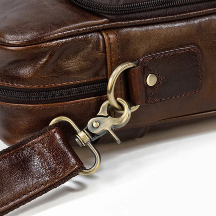 Close-up of the Leather 16" Briefcase in genuine cow leather, showcasing a metal swivel clasp and D-ring attached to the adjustable strap. The bag features a visible zipper and smooth leather texture with stitching details. The image highlights the craftsmanship and quality of the leather material.