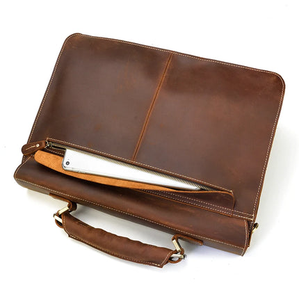 The Leather 16" Business Briefcase in brown genuine cowhide leather lies open, showcasing its spacious interior. A silver object is partially visible in the zippered compartment. Featuring sturdy handles and light-colored stitching along its seams, the briefcase also includes an adjustable strap for added convenience.