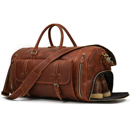 Introducing the Weekender 23 Leather Travel Bag, a stylish brown travel bag crafted from genuine cowhide leather. It features gold zippers, two front pockets, a top handle, and a long shoulder strap. Additionally, this bag includes an open side shoe compartment revealing a pair of beige and brown shoes inside.