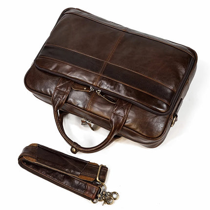 A Leather 16" Briefcase in large brown, made from genuine cow leather, sits against a white background. It showcases a visible zipper and sturdy handles, with an adjustable strap featuring metallic clasps on either end positioned beneath it.