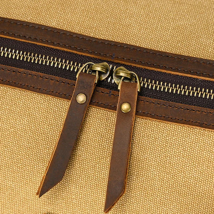 Close-up of the Canvas & Leather Travel Duffle reveals a vintage brown canvas bag with a zipper, dual metal sliders featuring brown leather pull tabs secured by brass rivets, and textured fabric that complements the genuine leather trim.