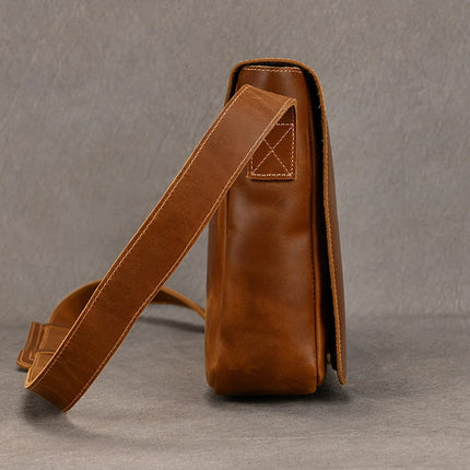Side view of the Vintage Leather Shoulder Bag, crafted from genuine cowhide leather and featuring a long, adjustable strap. The bag highlights visible stitching details and is set against a plain gray background, emphasizing its practical benefits.