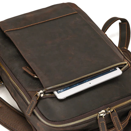 A Vintage Leather Daypack crafted from genuine cowhide leather in a rich brown color, showcasing detailed stitching and featuring multiple compartments. The front zippered pocket is shown partially open, revealing a tablet inside. The bag includes a zippered main compartment with a visible zipper pull and adjustable straps at the back for added convenience.