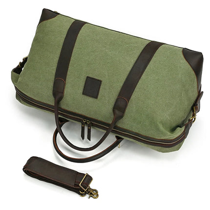 The Canvas & Leather Travel Duffle is a vintage green canvas bag with genuine leather straps and accents, including a rectangular leather patch on the side. It features a simple design and comes with a detachable shoulder strap.