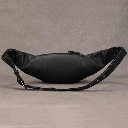 A Leather Belt Bag crafted from genuine black cowhide leather with an adjustable strap and a visible zipper lies against a textured gray background. The fashion expert’s choice, this bag features a sleek, minimalist design with a slight sheen on the leather surface.