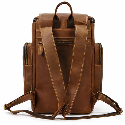 The Vintage Leather Travel Backpack is displayed from the back. Made of genuine cowhide leather, it includes two adjustable shoulder straps with intricate stitching detail, a convenient top handle, and numerous zipper compartments such as a central vertical zipper pocket and smaller side zipper pockets.