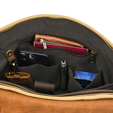 The Canvas & Leather Vintage Messenger Bag, featuring a business style similar to briefcases, showcases its contents: a brown leather-bound wallet, a smartphone pocket, a pen, tissues, and neatly arranged small items. Made from genuine leather with organized sections and a zippered pocket.