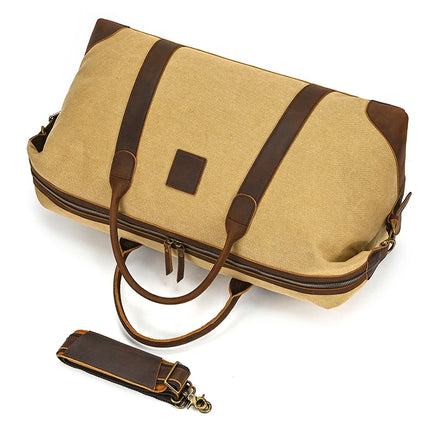 The Canvas & Leather Travel Duffle is a spacious vintage-style beige bag with genuine leather accents, dual handles, and dark brown detailing. It includes a detachable shoulder strap, bronze zippers, and a central rectangular leather patch.
