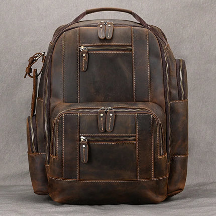 The Vintage Leather Travel Backpack showcases multiple zippered compartments and pockets. Made from authentic cowhide leather, it features a top handle, adjustable shoulder straps, and noticeable stitching details, all set against a plain grey background.