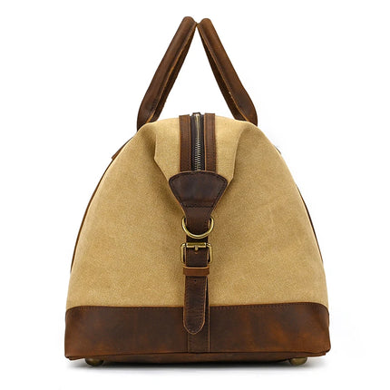 A side view of the Canvas & Leather Travel Duffle shows its tan canvas body with genuine dark brown leather accents, handles, and strap, enhanced by brass hardware for a vintage and rugged style.