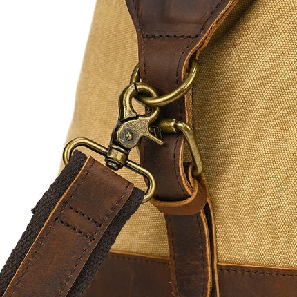 The Canvas & Leather Travel Duffle captures vintage charm with its genuine brown leather strap, secured by a brass swivel clip and ring. The beige canvas body exudes timeless elegance.