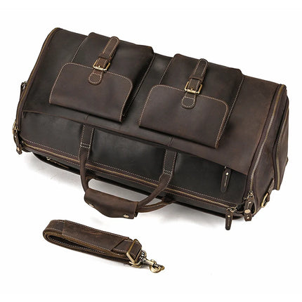 The Weekender 22 Leather Travel Duffle Bag is a large brown Genuine Cowhide Leather bag featuring two buckle flap pockets on the front, two sturdy handles, and reinforced stitching. It also includes an adjustable, detachable shoulder strap with a metal clasp and multiple zippers and compartments, including a convenient shoe compartment.