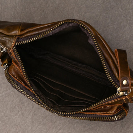 A top view of an open Leather Belt Bag, crafted from fashion expert-approved genuine cowhide leather and featuring a metal zipper. The dark interior is well-organized with multiple compartments. This sleek leather accessory is displayed on a textured gray surface.