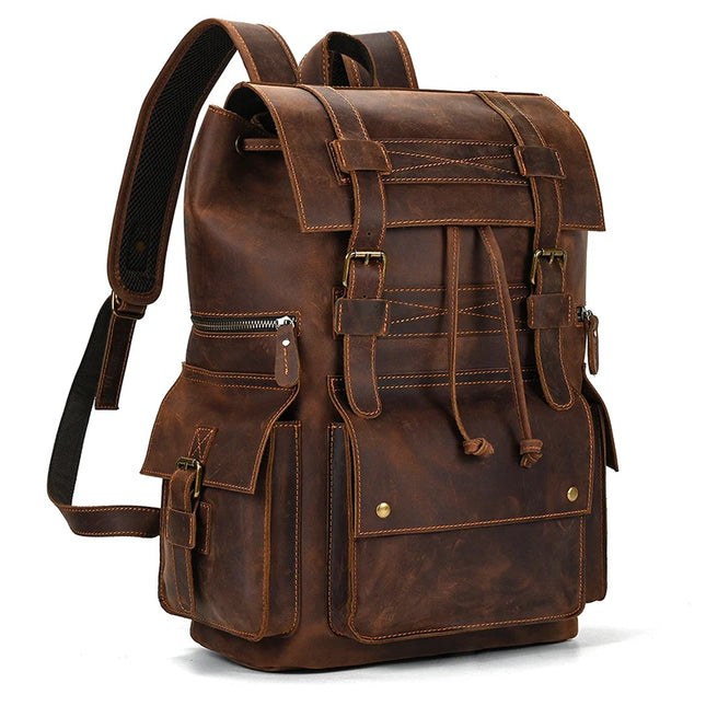 The Genuine Leather Travel Backpack in Light Brown boasts a vintage style, with two front pockets featuring buckled closures, a drawstring closure, adjustable shoulder straps, and a top flap secured by additional buckled straps. This durable travel gear showcases a rugged, worn appearance with visible stitching and metal hardware.