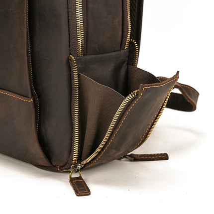 Close-up of the Vintage Leather Daypack in dark brown, showcasing its intricate design with sturdy golden zippers. The bottom compartment is partially open, revealing a spacious fabric-lined brown interior. The craftsmanship and smooth texture of the genuine cowhide leather are highlighted.