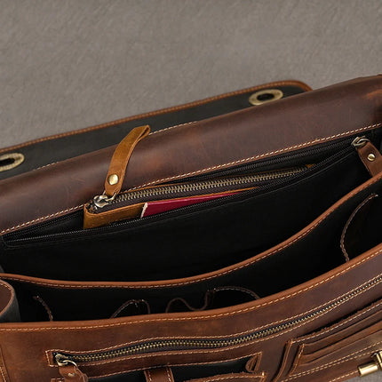 A close-up view of the interior of an open Vintage Business Travel Briefcase reveals multiple compartments, including a zippered pocket with a tan leather pull tab and a dedicated laptop compartment. The bag features a black lining, with an item boasting a red edge peeking out from one of the pockets.