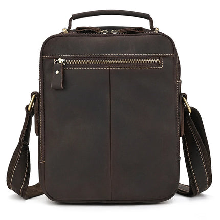 The Dark Brown Leather Shoulder Bag is a crossbody shoulder bag crafted from genuine cowhide leather, featuring a front zipper pocket, stitched detailing, and a small top handle. It also includes an adjustable shoulder strap with alloy hardware clips, all encapsulated in a sleek and minimalist design.
