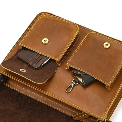 The Leather Business Travel Shoulder Bag features two flap pockets secured by premium alloy hardware. One pocket, shown open, contains a wallet and smartphone, while the other reveals a key holder with a metal clip. Crafted from authentic cowhide leather, the bag's interior is luxuriously lined with suede.