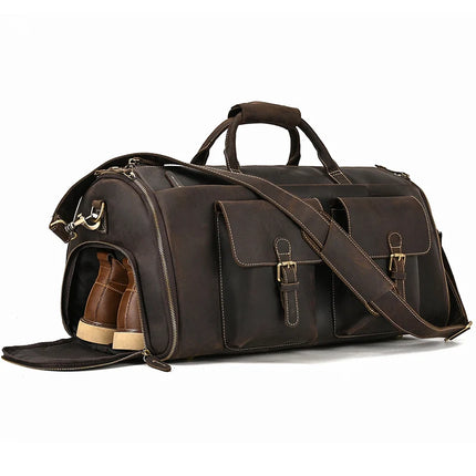 The Weekender 22 Leather Travel Duffle Bag is crafted from genuine cowhide leather and features two front pockets secured by buckles, a shoulder strap, and two handles. One side of the bag opens to reveal a pair of brown shoes stored within the dedicated shoe compartment. The bag is accentuated with contrast stitching and metal hardware for added durability and style.
