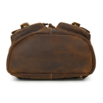 A Genuine Leather Vintage Backpack, radiating casual style, rests on a white background. Its slightly rounded and worn bottom adds character, while visible stitching and subtle brass accents highlight the authentic leather craftsmanship.