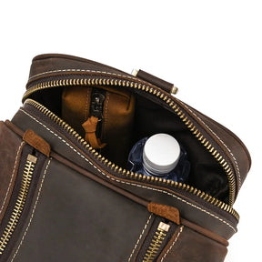 A close-up view of an open Luggage 24 Leather Travel Bag with a visible zipper. Inside this genuine leather bag, there is a small brown zipped pouch and a blue water bottle with a white cap. The stitching and texture of the leather are clearly visible, emphasizing its quality as a perfect travel bag.