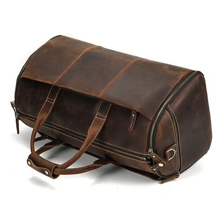 Introducing the Luggage 22 Leather Travel Duffle Bag, a large and dark brown *genuine leather* travel accessory with a sleek design. This duffle bag features double handles, a removable strap, and durable metal zippers that hint at its spacious compartments. With its vintage and rugged look highlighted by subtle signs of wear, this bag exudes an antique charm that's perfect for the seasoned traveler.