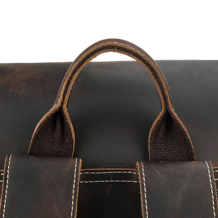 The Vintage Leather Travel Backpack features a close-up of its brown leather handle, highlighting the intricate stitching and texture of the genuine cowhide leather. The robust and well-crafted handle shows visible stitching on both itself and the attached straps, underscoring the quality craftsmanship of this vintage travel backpack that includes a hidden laptop compartment.
