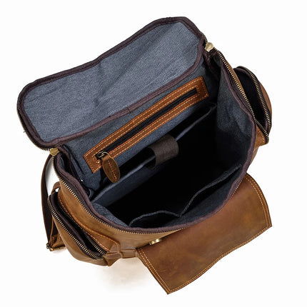 The Vintage Leather Travel Backpack features two large compartments, a smaller zippered pocket on one internal side, and a padded gray lining. The flap is open to reveal the organized interior, perfect for carrying documents, tablets, and other small items. Crafted from genuine cowhide leather.