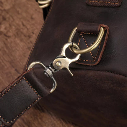 Close-up of the Vintage Leather Travel Backpack, crafted from dark brown genuine cowhide leather and featuring a metallic clasp with a ring attachment. The bag showcases detailed stitching and boasts a rugged, vintage look, making it ideal for the stylish traveler. Set against a wooden background, it perfectly exemplifies both durability and elegance.