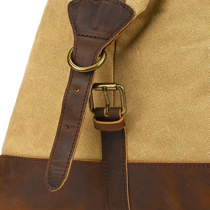 Close-up of the Canvas & Leather Travel Duffle showcasing its canvas material paired with a genuine brown leather strap and buckle, contrasted against the lighter fabric. A brass-colored metal ring enhances its vintage charm.