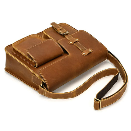 The Leather Business Travel Shoulder Bag is made from genuine cowhide leather and features an adjustable strap, alloy hardware, and two front compartments secured by buckles. Additionally, it includes a small front pouch. The bag has a smooth finish with light brown stitching along the edges, making it ideal for business travel.