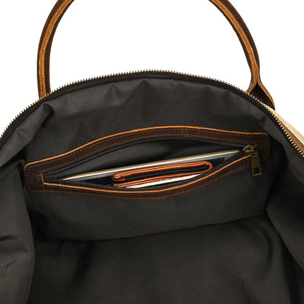A peek inside a genuine leather black handbag reveals a pocket with a wallet and smartphone. The brown leather handles and zipper accents enhance its vintage appeal. Product Name: Canvas & Leather Travel Duffle.
