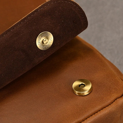 Close-up image of the Vintage Leather Shoulder Bag with a flap featuring a brass snap button closure. The top flap is partially open, displaying the words "Open, Close" etched around the button on the genuine cowhide leather flap. The golden snap button on the main body of the bag is in focus.