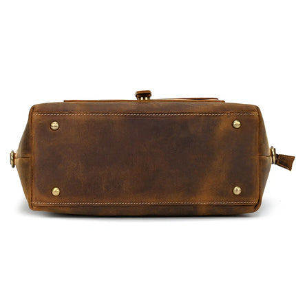 The underside of the Genuine Leather Women's Tote Bag – Large Capacity Business Handbag showcases a rectangular shape accented by four brass feet. Its aged leather texture enhances the classic charm, while a small leather loop on the side adds both style and practicality to this women's tote.
