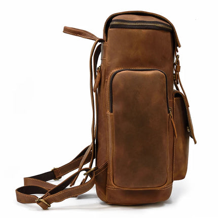 The Vintage Leather Travel Backpack is a sophisticated piece made from authentic cowhide leather, designed with multiple compartments and adjustable straps. It boasts a main zippered compartment that houses a laptop section, along with two extra zippered pockets on the side and front. Its elegant vertical design is enhanced by brass buckles and accents.